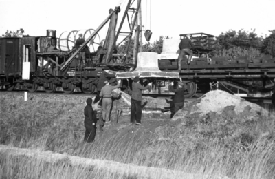 164318 Afbeelding van het plaatsen van een betonnen voet voor een bovenleidingsmast langs de spoorlijn tussen Breda en ...