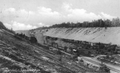 161221 Gezicht in de ingraving van de spoorlijn te Nijverdal, met een trein getrokken door een stoomlocomotief uit de ...