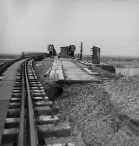 158890 Gezicht op de spoorbaan te Gennep, uit het oosten. In het midden de plaats van de in de oorlog vernielde ...