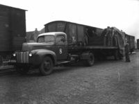 160638 Afbeelidng van het overladen van goederen van een vrachtauto op de trein op de laad- en losplaats van het ...