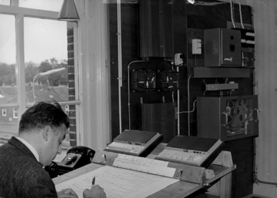 156458 Afbeelding van de treindienstleider in de Centrale Radio Verkeersleidingspost (CRVL-post) in het N.S.-station ...