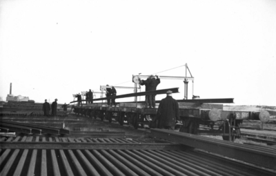164325 Afbeelding van het beladen van enkele wagens met spoorstaven op de stapelplaats van de N.S. te Crailoo.