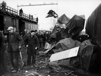 157536 Afbeelding van de onder dekzeilen naast de spoorlijn opgestelde wrakstukken van de bij de treinramp te Harmelen ...