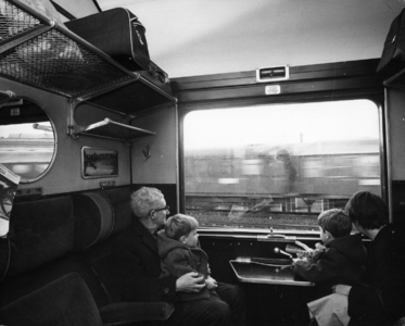 156348 Afbeelding van een opa met kleinkinderen en dochter in de coupé van een internationaal rijtuig.