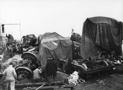 157535 Afbeelding van de onder dekzeilen naast de spoorlijn opgestelde wrakstukken van de bij de treinramp te Harmelen ...