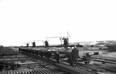164324 Afbeelding van het beladen van enkele wagens met spoorstaven op de stapelplaats van de N.S. te Crailoo.