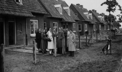 26260 Afbeelding van enkele excursiegangers bij een rijtje nieuwe gemeentewoningen aan de Nijkerkerweg te Bunschoten. ...