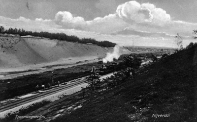 161417 Gezicht in de ingraving van de spoorlijn te Nijverdal, met een passerende trein getrokken door een ...