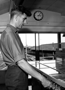 156463 Afbeelding van de seinhuiswachter bij een stelknoptoestel in het seinhuis Post H van de N.S. op het ...