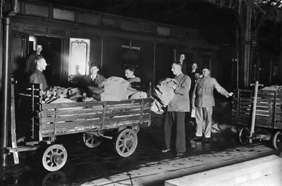 152037 Afbeelding van het nachtelijke in- en uitladen van de post uit een postrijtuig van de Nederlandse Posterijen op ...