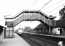 150589 Gezicht op perrons en de voetgangersbrug van het N.S.-station Putten te Putten, met een naderende trein ...