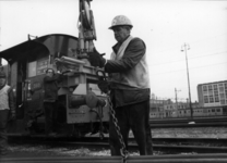 153421 Afbeelding van een wegwerker van de N.S. tijdens het gebruik van de hydraulische kraan van locomotor nr. 360 ...