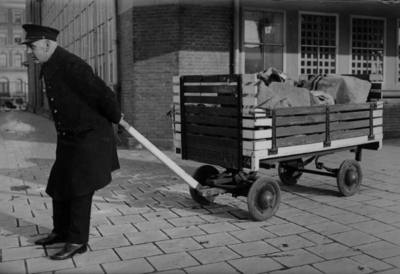 160635 Afbeelding van een beambte van de P.T.T. met een postkar bij het Stationspostkantoor (Laan van Puntenburg 5) te ...