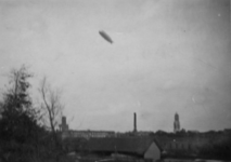 123258 Gezicht op het Duitse luchtschip Graf Zeppelin op doorreis boven Utrecht; rechts van het midden de Domtoren.