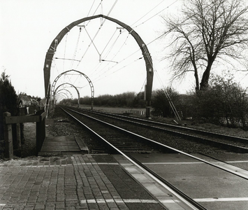 92574 Gezicht op de bovenleidingsportalen in de spoorlijn Utrecht-Hilversum bij de spoorwegovergang in de ...