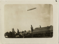 125062 Gezicht op het Duitse luchtschip Graf Zeppelin op doorreis boven Utrecht; op de voorgrond een gedeelte van de ...