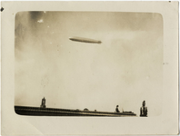 125063 Gezicht op het Duitse luchtschip Graf Zeppelin op doorreis boven Utrecht; op de voorgrond een gedeelte van de ...