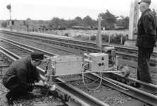 167444 Afbeelding van een wegwerker van de N.S. tijdens het solderen van een retourstroomverbinding tussen twee ...