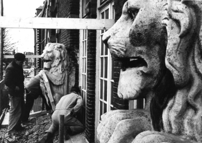 600503 Afbeelding van het verwijderen van de wapendragende leeuwen boven de hoofdingang van de voor sloop bestemde Van ...