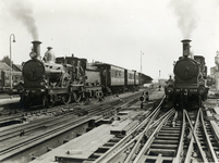 170077 Afbeelding van een stoomlocomotief uit de serie 1300/1400 van de N.S. (links) met een trein te Apeldoorn. Rechts ...